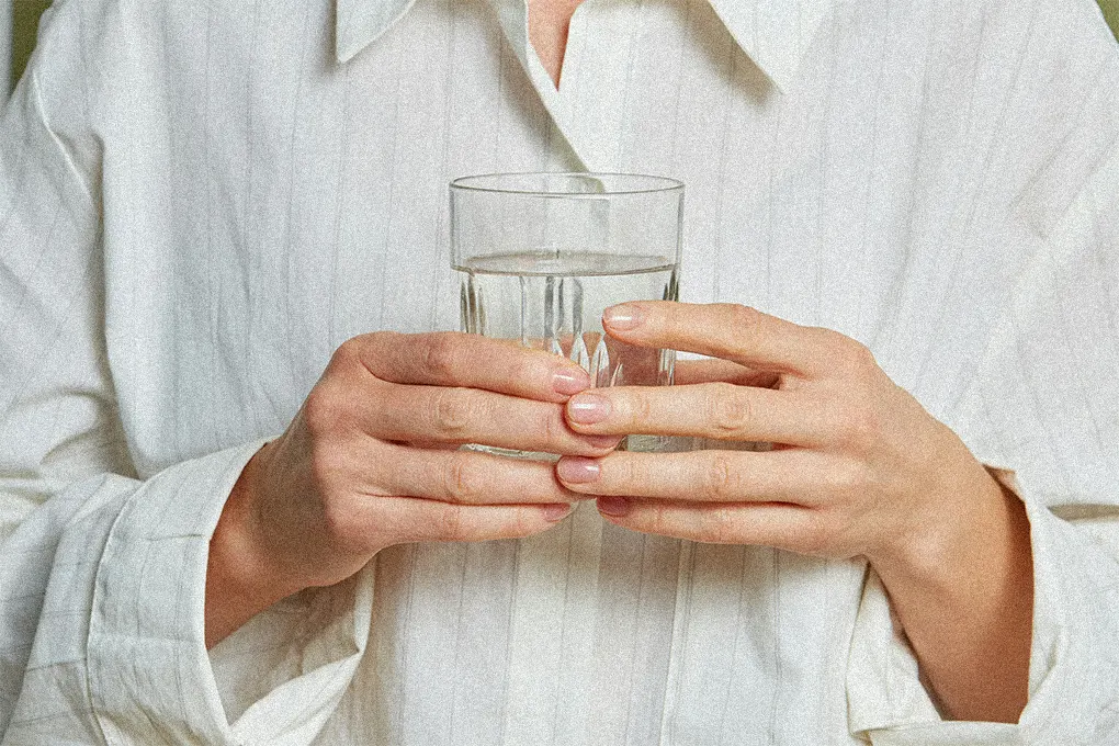 older person holding a glass of water