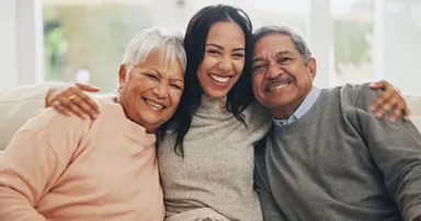 portrait of smiling older adults with daughter in Daly City lounging in the sofa