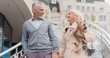 A senior couple taking a stroll outside their Hillsborough home while the senior female is holding a dog