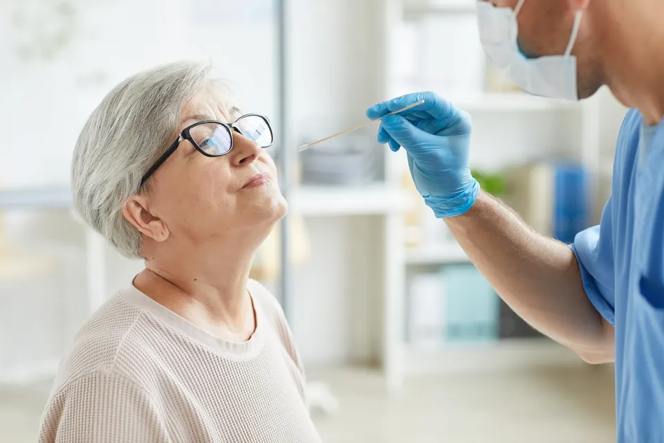 A healthcare worker administers a COVID-19 test to an elderly woman using a nasal swab.